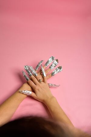 The procedure for removing varnish from nails hybrid nails in progress. Gel nail polish remover foils on woman's handsの写真素材