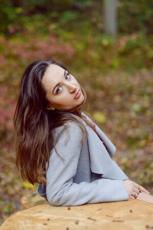 Woman standing next to a tree in park in golden autumn.の写真素材