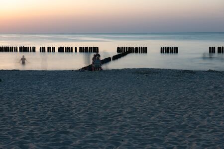 A photograph of wooden breakwater and seagulls at sunset on the Baltic Seaの写真素材