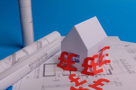 White family paper house , british pound money symbol , house projects plan and blueprints on mint background paper. Minimalistic and simple concept, style. Vertical orientation. View from above. copy spaceの写真素材