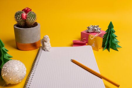 gift box and green origami trees with notepad on yellow desk, tableの写真素材
