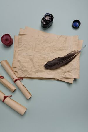 Raven feather, inkwell and old yellowed paper on red background. Copy space. Old letter.の写真素材