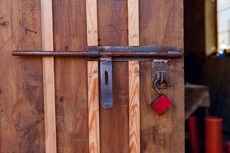 Old red padlock on a wooden doorの写真素材