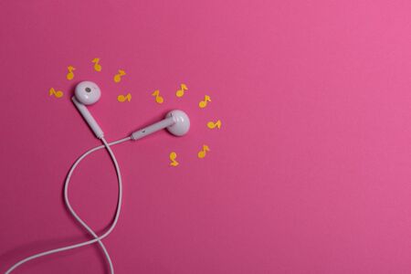 white earphones and white paper notes on orange background. view from aboveの写真素材