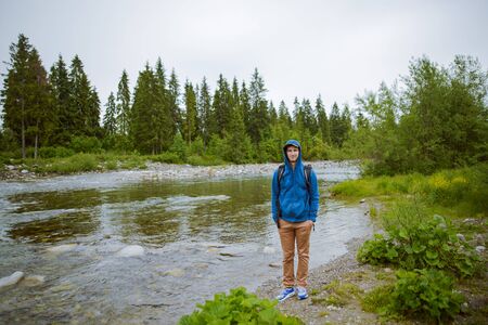 male tourist standing beside the mountain river.の写真素材