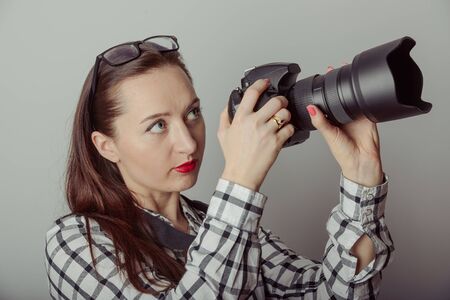 Woman-photographer takes images, isolated on gray background