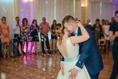 Bride and groom dancing the first dance at their wedding day. Guest on the dancefloorの写真素材