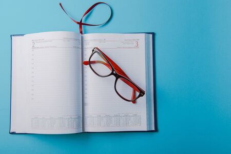 Business planning with copy space and office supplies. Red glasses on blue backgroundの写真素材