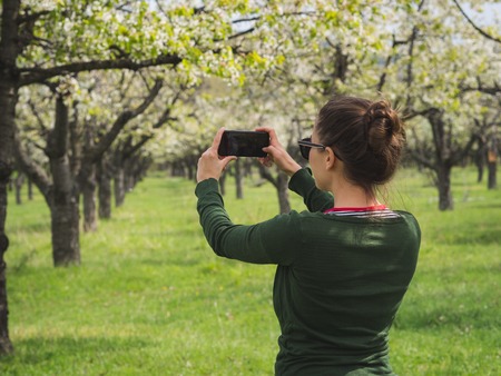 Young woman taking a picture of the view while hiking in a national park with a smart phoneの写真素材