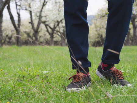 Close-up of mans legs in stylish sneakers on green grass