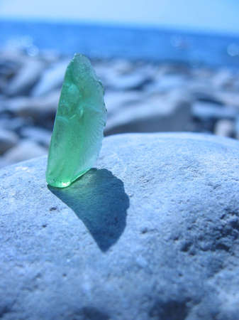 green glass on the gray stone at the beachの写真素材