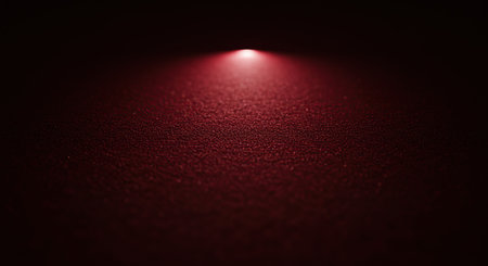 A single, bright red spotlight shines down on a dark, textured wall, creating a dramatic and atmospheric effect with a focused beam of light.の素材