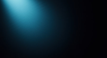 A powerful blue spotlight shines from the top left, casting a dramatic beam across a dark, textured surface with a gradient effect.の素材