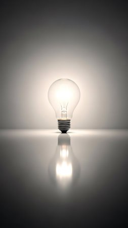 Incandescent light bulb on a white background with reflection and copy spaceの素材
