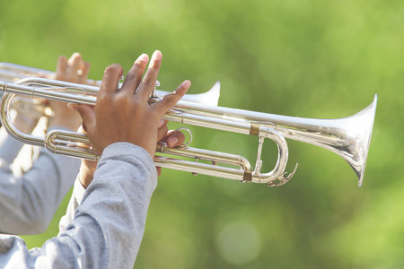 Closeup of Hands Holding the Trumpets with Green Natural Backgroundの写真素材