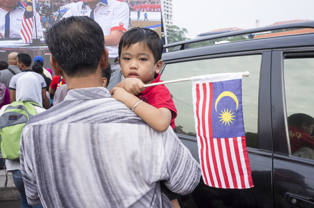 KUALA LUMPUR, MALAYSIA - AUGUST 31: Unidentified young boy look to camera while his hand hold Malaysia national flag during celebration of 57th Independence Day in Merdeka square, Kuala Lumpur, Malaysia on August 31, 2014のeditorial素材