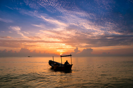 Silhouette of traditional Malaysian fisherman preparing his boat in the morningの写真素材