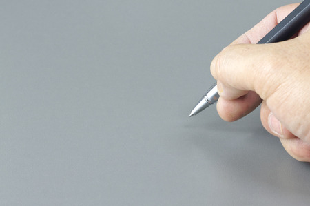 Close up of Pen and Hand Isolated on grey background