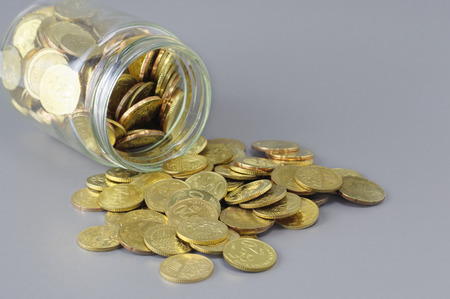 Gold Coins spilling out of jar - Business Conceptの写真素材