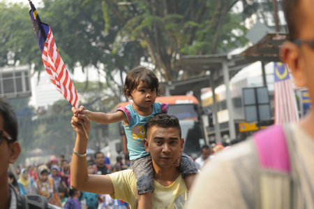 KUALA LUMPUR, MALAYSIA - AUGUST 31: Unidentified young father carriying his young girl holding Malaysia national flag during celebration of Malaysia Independence day 58th in Merdeka square, Kuala Lumpur, Malaysia on August 31, 2015のeditorial素材