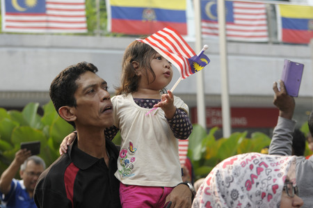 KUALA LUMPUR, MALAYSIA - AUGUST 31: Unidentified father holding his young girl waving Malaysia national flag during celebration of Malaysia Independence day 58th in Merdeka square, Kuala Lumpur, Malaysia on August 31, 2015のeditorial素材