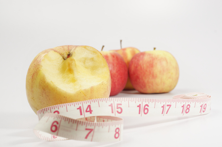 Close up view bitten red apple and measurement tape isolated on white backgroundの写真素材