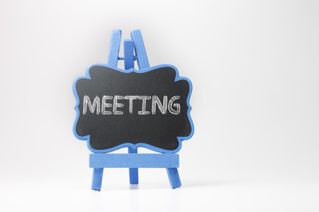 Meeting text on blackboard isolated on white backgroundの写真素材