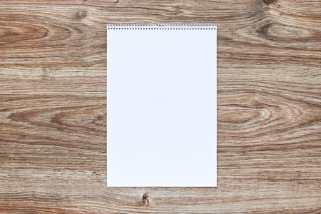 Mockup of open album with blank white page on wooden background. Vertical orientation, top view.の写真素材