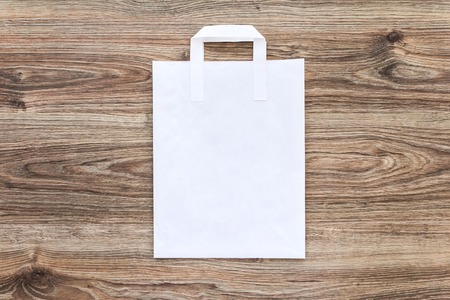 Blank of paper shopping bag on the wooden background. Mock up for your designの写真素材