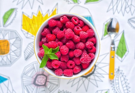 Raspberries in ceramic bowl. Top view. Ripe and tasty raspberries on a wooden background.