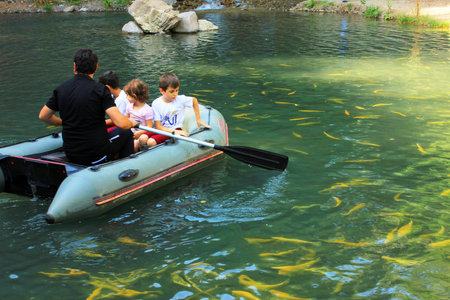 Oguz. Azerbaijan. 08/27/2016. A man rides children in an inflatable boat at a waterfall.のeditorial素材