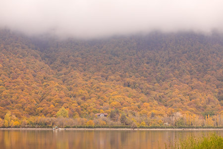 Lake Garanohur. Gabala region. Azerbaijan. 10.31.2021. House on the lake with yellow trees on the mountain.のeditorial素材