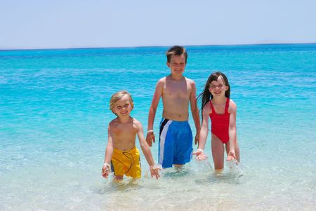 Three Children Wading in Oceanの写真素材