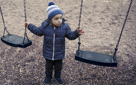 Adorable little 2-3 year old boy having fun on playground, child wearing blue hoody jacket and blue capの写真素材