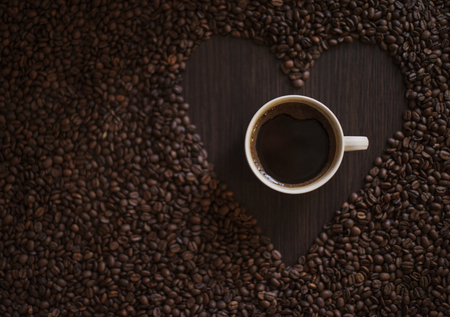 Hot Coffee cup with Coffee beans on the wooden tableの写真素材