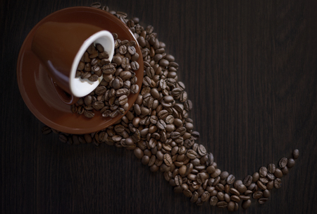 Brown coffee cup and coffee beans on wooden table. Coffee beans close up. Coffee background. Coffee addiction.の写真素材