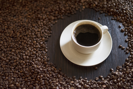 Coffee cup and coffee beans on wooden table. Coffee beans close up.の写真素材