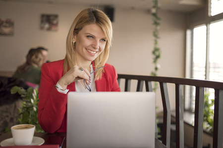 Business woman is working on laptop and drinking cup of coffee in coffee shopの写真素材