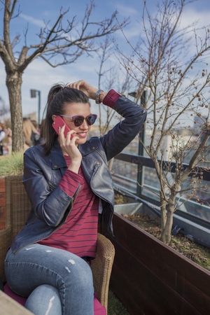 Beautiful smiling young woman sitting outdoors and talking on mobile phone. Girls time, enjoying, lifestyle.の写真素材
