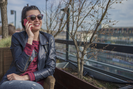 Beautiful smiling young woman sitting outdoors and talking on mobile phone. Girls time, enjoying, lifestyle.の写真素材