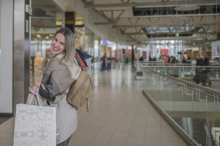 Smiling girl with Shopping Bags in Shopping Mall. Fashion Shopping Girl Portrait. Beauty Woman with Shopping Bags in Shopping Mall. Shopper. Sales. Shopping Centerの写真素材