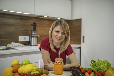 Young woman drinking smoothie in the kitchen. Close up portrait of young woman in the kitchen. Healthy Food - Vegetable Salad. Diet. Dieting Concept. Healthy Lifestyle. Cooking At Home. Prepare Foodの写真素材