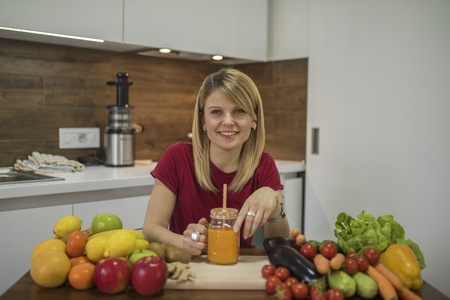 Young woman drinking smoothie in the kitchen. Close up portrait of young woman in the kitchen. Healthy Food - Vegetable Salad. Diet. Dieting Concept. Healthy Lifestyle. Cooking At Home. Prepare Foodの写真素材