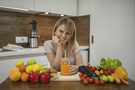 Young woman drinking smoothie in the kitchen. Close up portrait of young woman in the kitchen. Healthy Food - Vegetable Salad. Diet. Dieting Concept. Healthy Lifestyle. Cooking At Home. Prepare Foodの写真素材