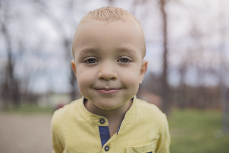 Adorable little boy having fun on playground. Active sport leisure for kids outdoor in park. Little boy with blue eyes in yellow shirt playing and having fun on playground.の写真素材