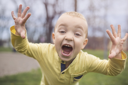 Adorable little boy having fun on playground. Active sport leisure for kids outdoor in park. Little boy with blue eyes in yellow shirt playing and having fun on playground.の写真素材