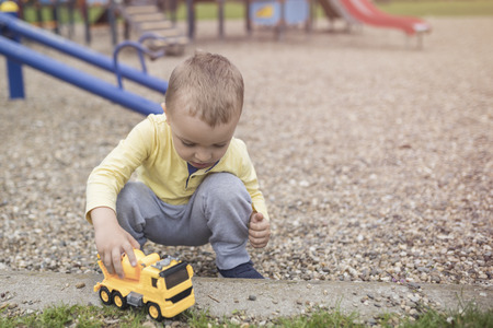 Adorable little boy having fun on playground. Active sport leisure for kids outdoor in park. Little boy with blue eyes in yellow shirt playing and having fun on playground.
