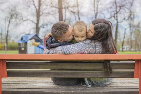 Parents having fun with their child in park. Beautiful family is having fun outside. Mom with dad are playing with their little son on playground. Adorable little boy enjoying with his parents. の写真素材