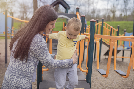Closeup portrait of a happy mother and son playing on playground and having fun. Young mother playing with her baby boy outside in park. Mom and son. の写真素材