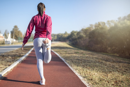 Young fitness woman runner athlete. Girl  jogger training and doing workout outdoors in city.